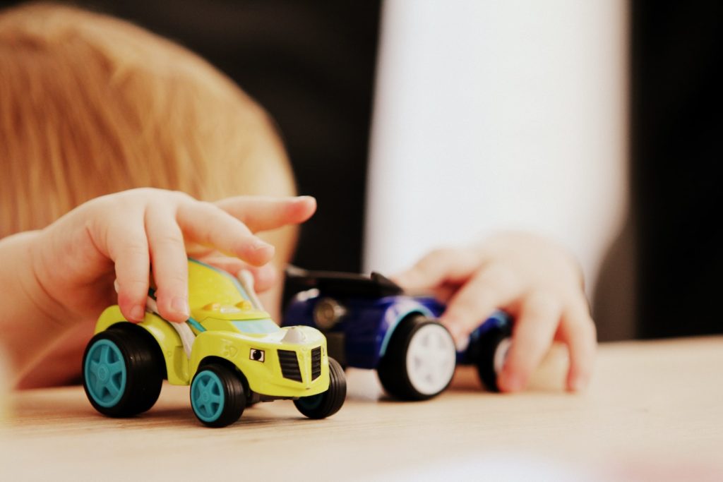 child playing with two cars